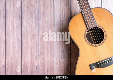 Acoustic guitar resting on rustic wooden background. Copy space. Stock Photo
