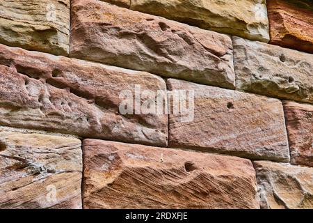 Large textured stone brick wall with earth tone hues and rustic red abstract background asset Stock Photo