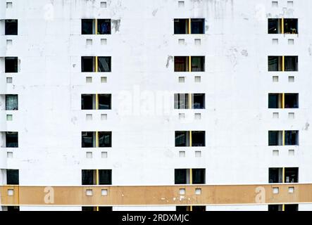 Wall outside of an old condominium or apartment with cracked wall, old texture, weathered condition, old painted and pattern of windows. Stock Photo