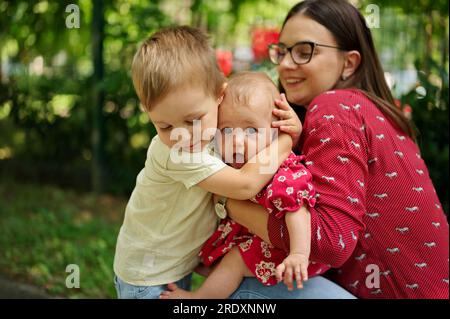 Mother and two children cuddling in a park Stock Photo