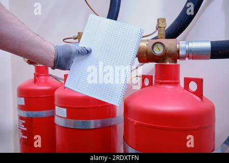 The man in charge of fire prevention and protection is conducting an inspection of the gas systems by inspecting all hand-held fire extinguishers. Stock Photo