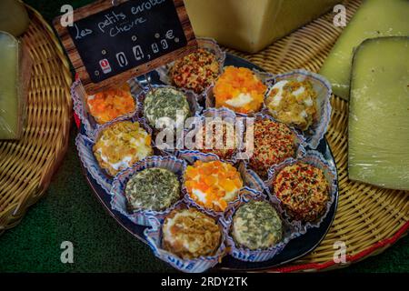 Coated goat cheese rounds with chives, herbs, dried apricots and raisins at an artisanal cheese shop in the old town or Vieil Antibes, South of France Stock Photo