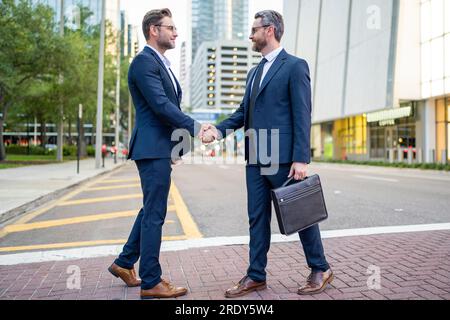 Businessmen in suit shaking hands outdoors. Handshake between two businessmen. wo business men had business contacts. Business men have a meeting Stock Photo