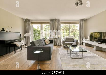 a living room with couches, coffee table, and piano in the middle part of the room is empty Stock Photo