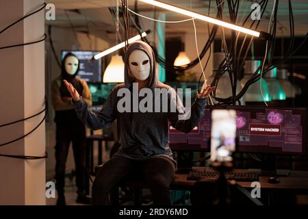Online criminal calling victim, threatening on phone camera, internet fraud. Cybercrime, scam, hacker asking for money, stealing banking information, taking video on smartphone at night time Stock Photo