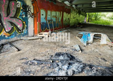 Contrasts between human detritus and ugliness, with nature's serene woodland.This image of graffiti by the Thames near Oxford does not show the traffi Stock Photo