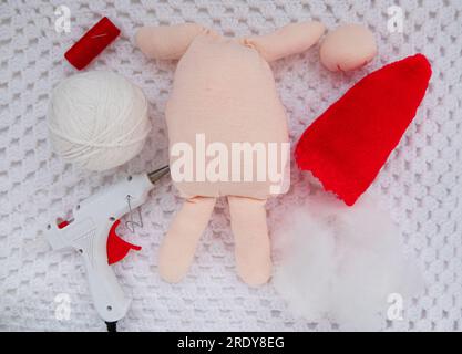 Scandinavian gnome with long beard red hat white knit background step by step handmade tutorial. Homemade fabric swedish Christmas decoration DIY. Hob Stock Photo