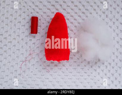 Scandinavian gnome with long beard red hat white knit background step by step handmade tutorial. Homemade fabric swedish Christmas decoration DIY. Hob Stock Photo