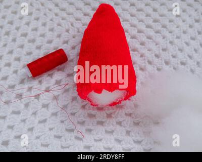 Scandinavian gnome with long beard red hat white knit background step by step handmade tutorial. Homemade fabric swedish Christmas decoration DIY. Hob Stock Photo