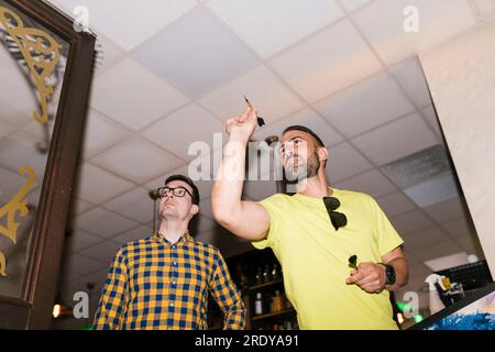 Man aiming dart on target standing next to friend at bar Stock Photo