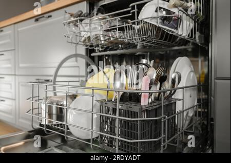 Clean dishes and cutlery inside dishwasher Stock Photo