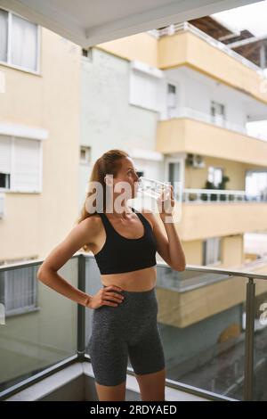 Young woman drinking water in balcony Stock Photo