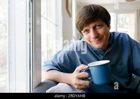 Smiling man drinking tea in living room Stock Photo