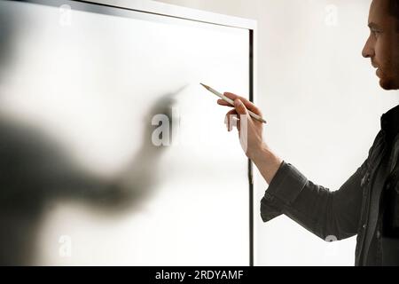 Businessman with digitized pen writing on interactive whiteboard Stock Photo