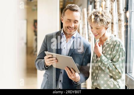 Happy business colleagues discussing over tablet PC Stock Photo