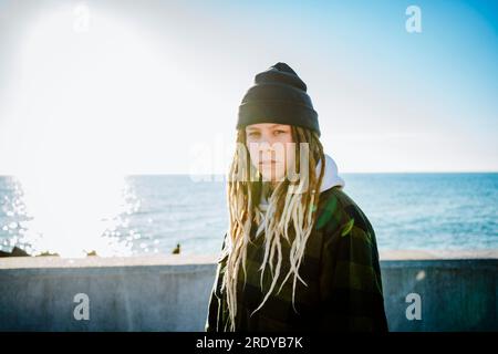 Young woman with dreadlocks standing near sea Stock Photo