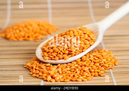 A wooden spoon filled with lentils on top of a bamboo mat Stock Photo