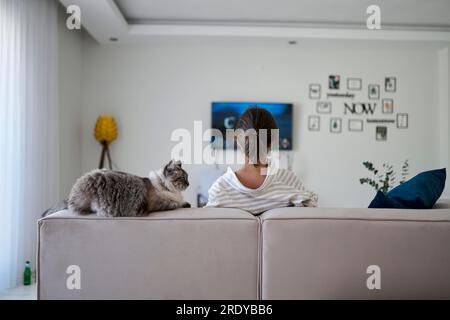 Woman with cat sitting on sofa at home Stock Photo