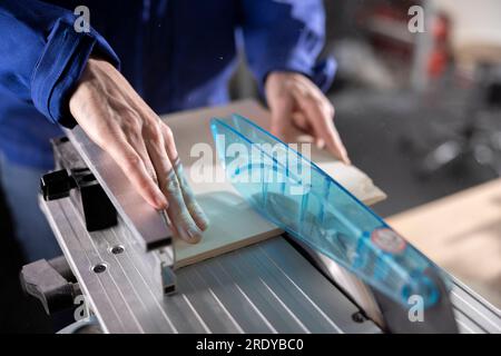 Hands of carpenter measuring wood through level at workshop Stock Photo