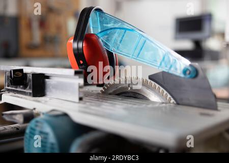Circular saw with ear protectors in workshop Stock Photo