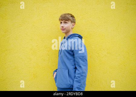 Thoughtful boy standing in front of yellow wall Stock Photo