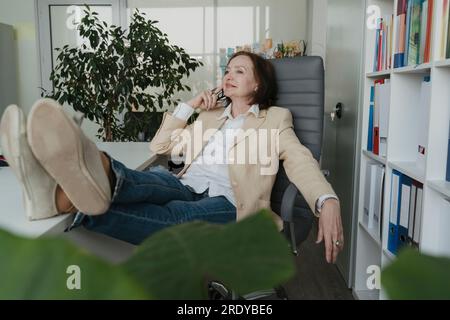 Thoughtful senior businesswoman relaxing on chair in office Stock Photo