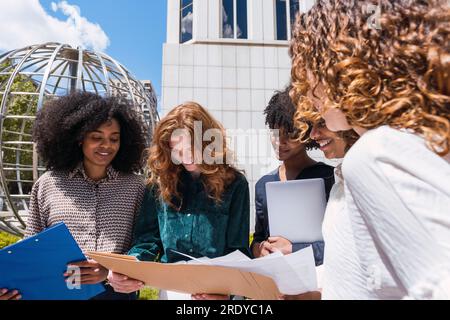 Happy businesswoman having discussion over documents with colleagues Stock Photo