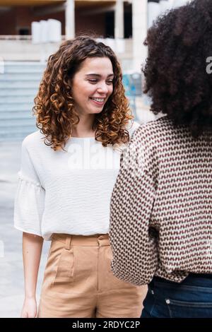 Smiling young businesswoman standing with colleague in office park Stock Photo