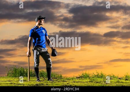 Man standing with baseball bat at dusk Stock Photo