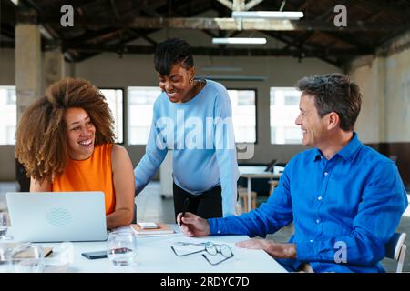 Happy mature businessman working and having discussion with colleagues Stock Photo