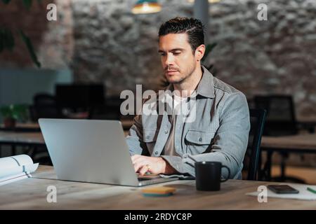 Architect using laptop sitting on table in office Stock Photo
