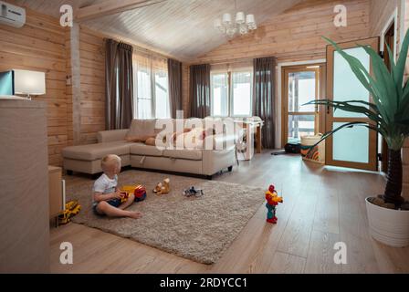 Son playing with toys sitting on carpet in living room at home Stock Photo