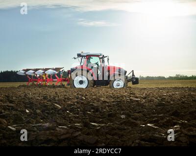 Farmer plowing field using tractor at sunrise Stock Photo