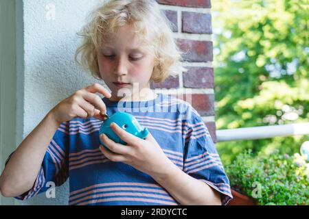 Boy putting coin in piggy bank Stock Photo