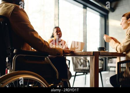Businessman in wheelchair discussing with coworkers at conference table Stock Photo