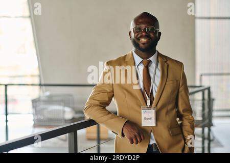 Confident smiling businessman in suit standing at convention center Stock Photo