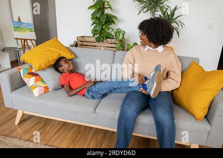 Happy mother with son lying on sofa at home Stock Photo