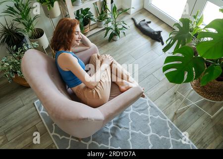 Happy woman relaxing on armchair at home Stock Photo