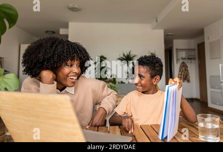 Happy son showing homework to mother at home Stock Photo