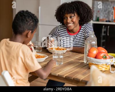 Smiling mother and son having meal together at home Stock Photo