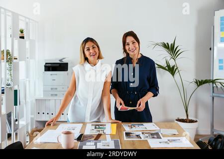 Smiling businesswomen with documents at desk in creative office Stock Photo