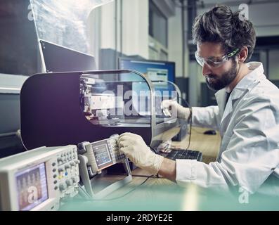 Technician operating 3d printing machine in laboratory Stock Photo