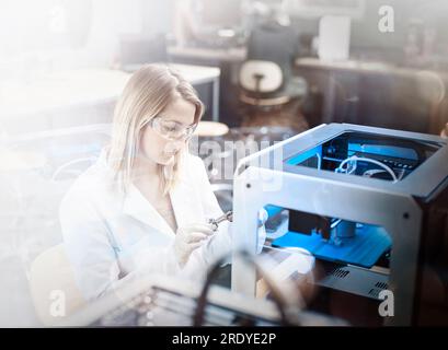 Engineer examining 3d printer in laboratory Stock Photo