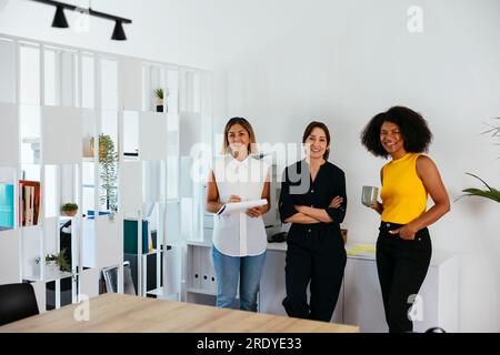 Team of happy businesswomen standing in creative office Stock Photo