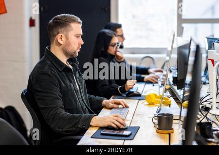Businessman working on computer with colleagues in background Stock Photo