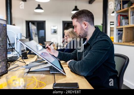 Architect working on graphics tablet at desk Stock Photo