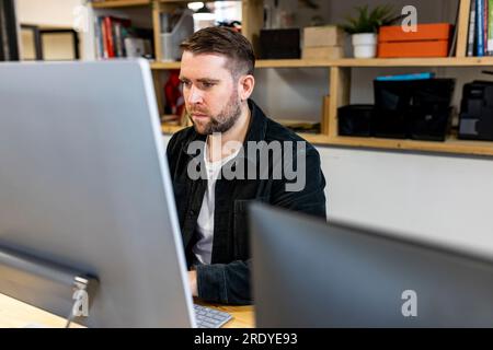 Businessman working on desktop PC in office Stock Photo