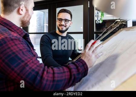Happy architects working on blueprint in office Stock Photo