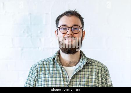Smiling young businessman wearing eyeglasses in front of white wall Stock Photo