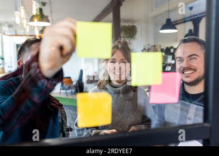 Happy businessmen and businesswoman discussing over adhesive notes Stock Photo